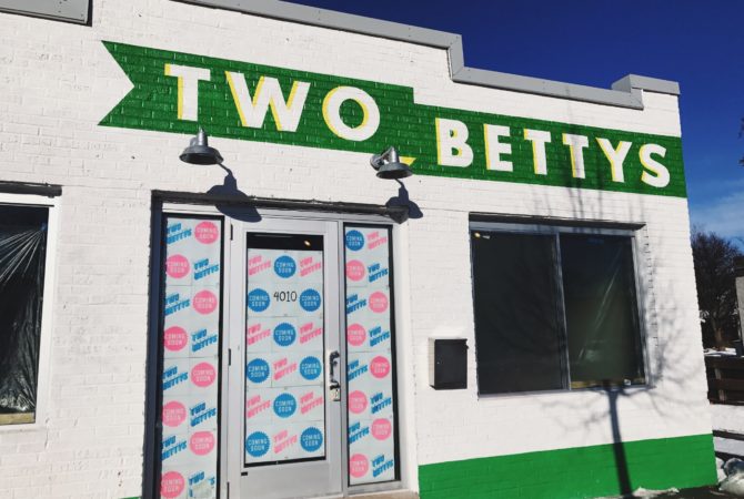 The front face of Two Bettys Refill Station featuring a green and white logo across the top of the building