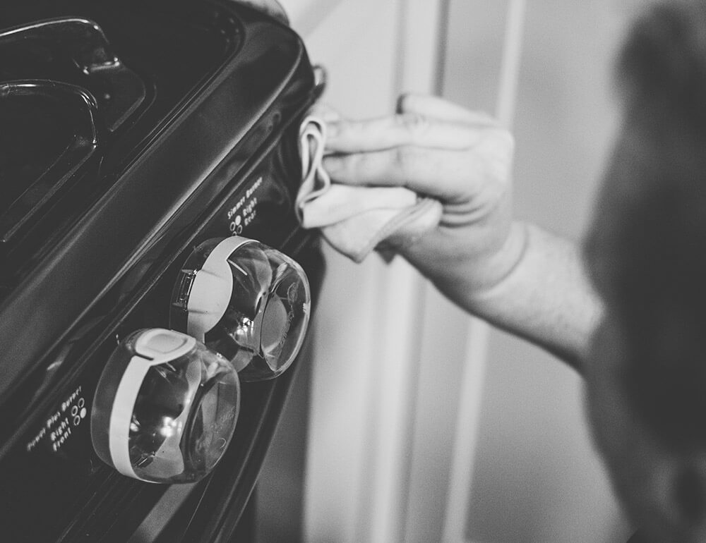 Black and white close-up of a cleaner wiping down an oven