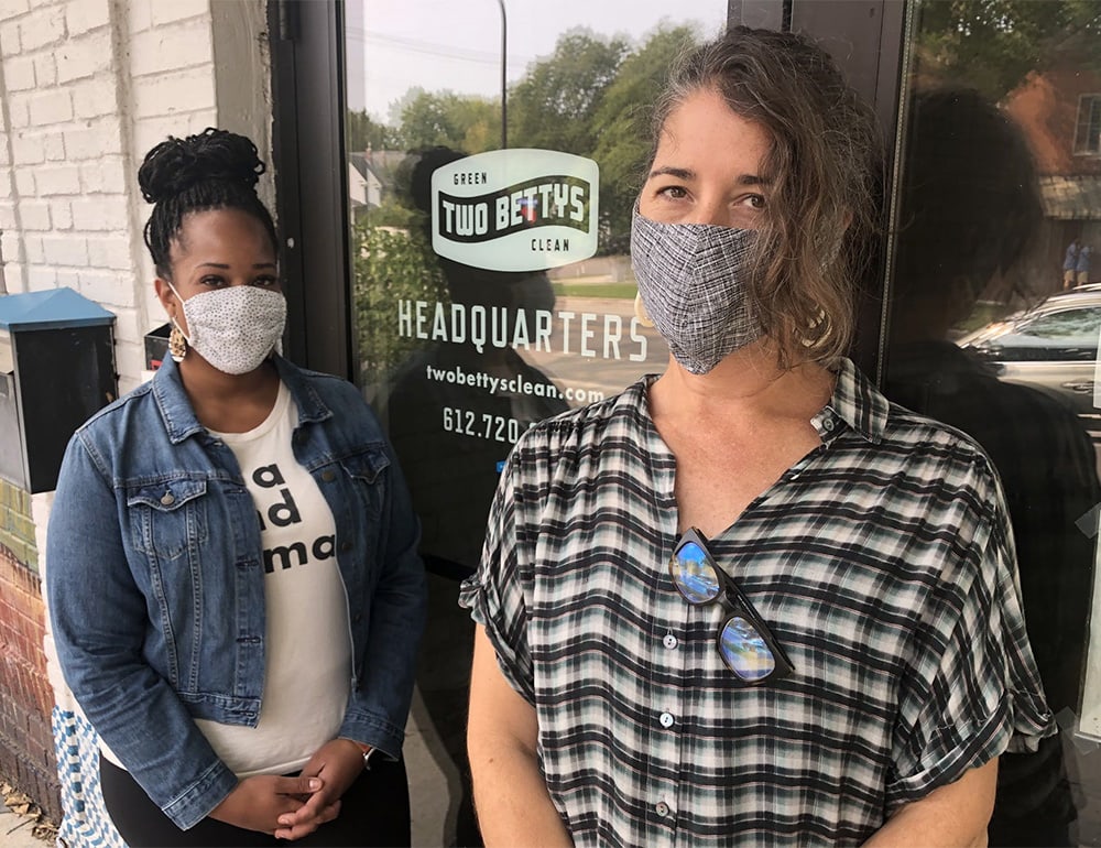 Two women, one black and one white, wearing masks, standing in front of Two Bettys Green Cleaning