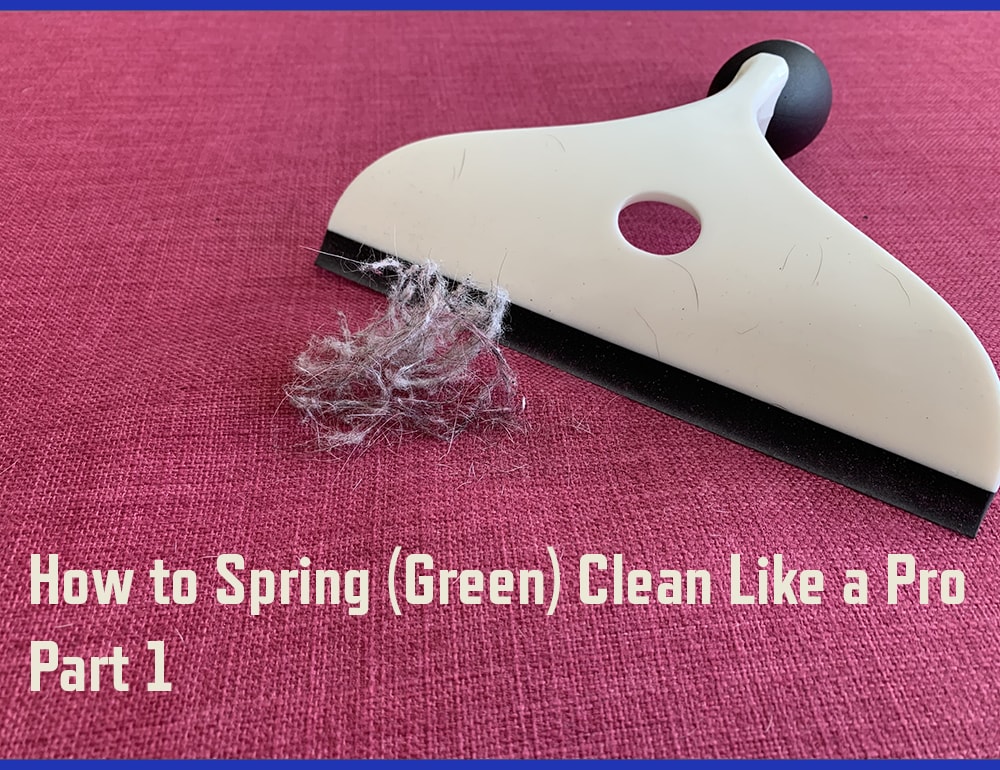 A black and white squeegee and small pile of fur and dust on a pink fabric surface